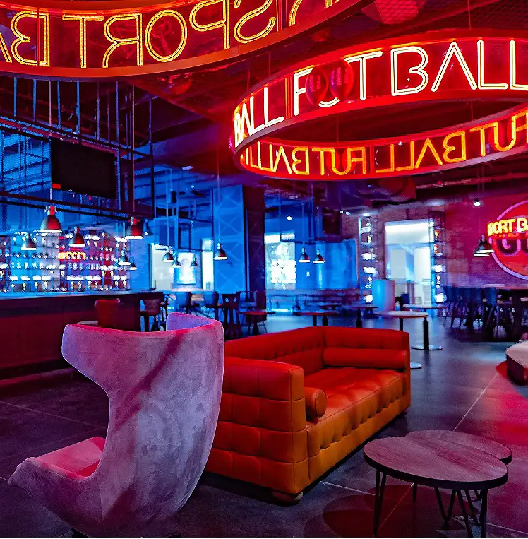Sala con sillones rojos y letreros luminosos en un bar tipo casino