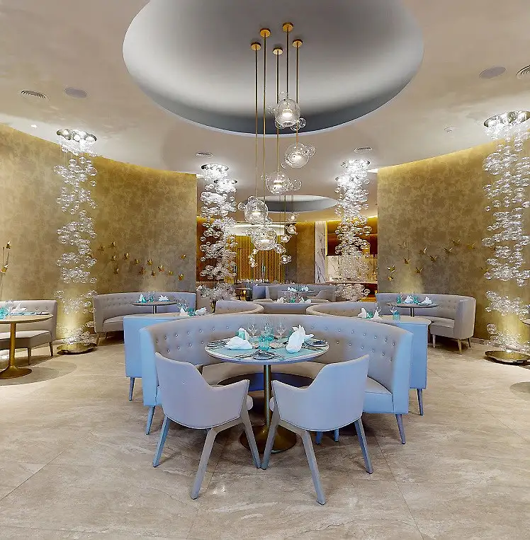 Comedor de lujo con mesas azules y candelabros de cristal dorados en sal&oacute;n