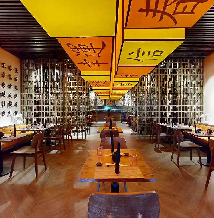 Interior de museo chino con mesas, bancos y banderines amarillos y naranjas