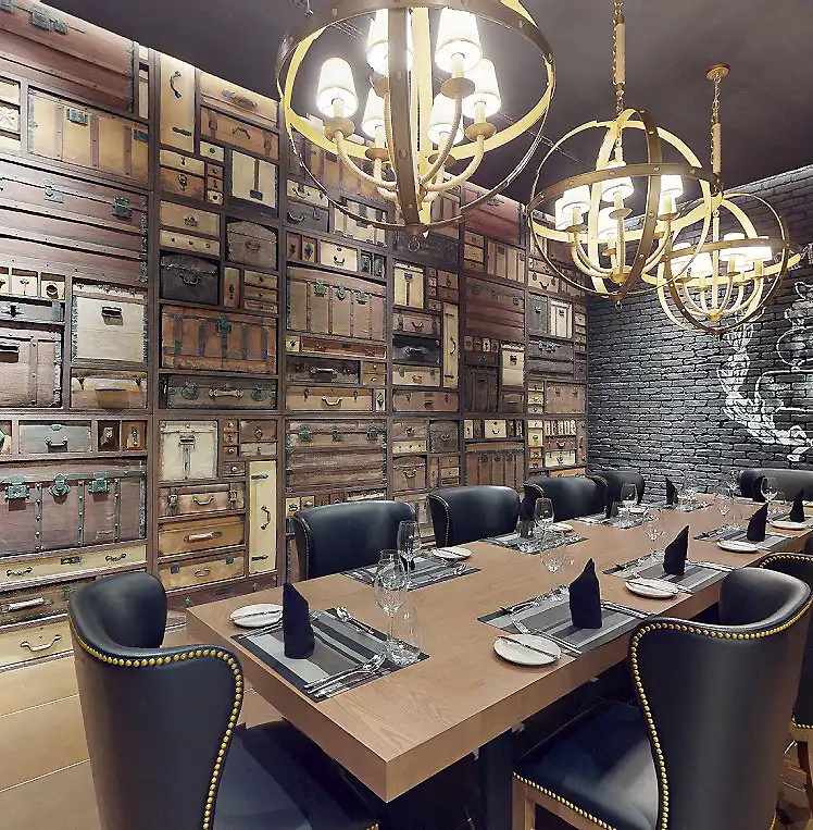 Sala de reuniones con mesas, sillas y candelabros dorados sobre pared de cajones