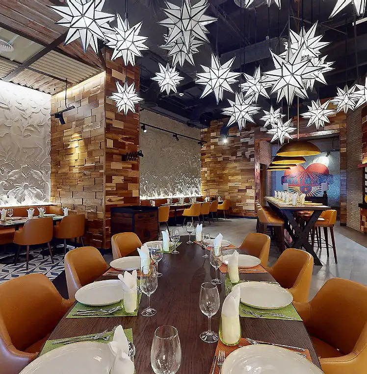 Comedor moderno con mesas servidas y decoraci&oacute;n de estrellas colgantes.
