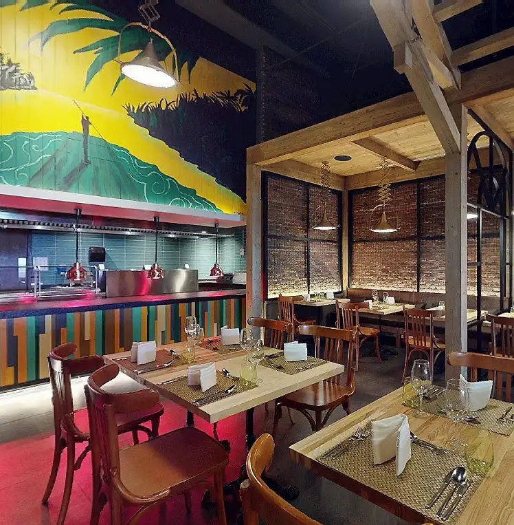 Interior de restaurante con mesas, sillas y pared mural tropical.