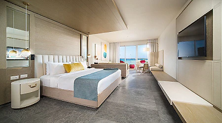 Habitaci&oacute;n hotelera moderna con cama doble y televisi&oacute;n en la pared