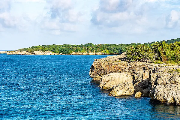 Bah&iacute;a con acantilados rocosos y vegetaci&oacute;n junto al mar azul