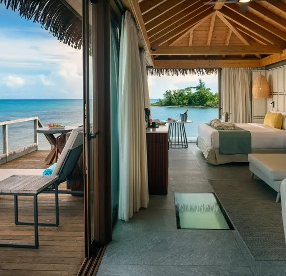 Terraza frente al mar con cama y cortinas, mesa y vista a la bah&iacute;a