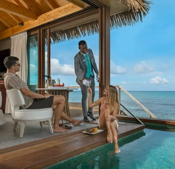 Hombre y dos personas junto a piscina en una caba&ntilde;a frente al mar