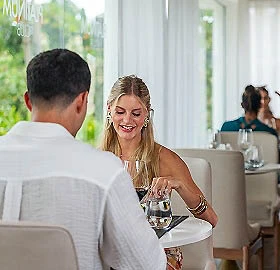 Mujer sonriente brinda con una copa en un restaurante con luz natural