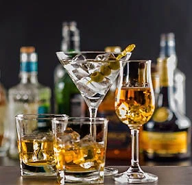 C&oacute;cteles con hielo y botellas de licor en una barra oscura