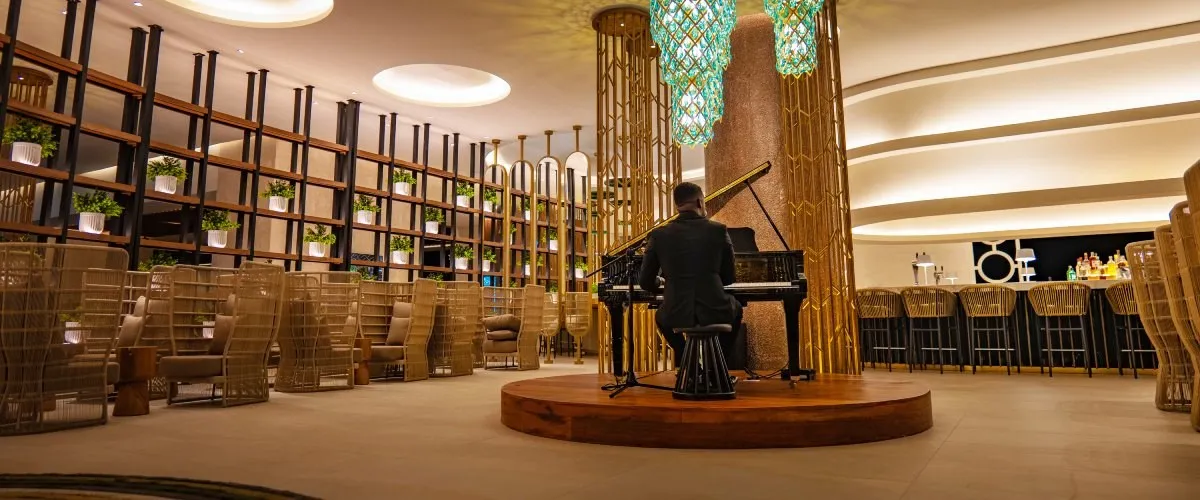 M&uacute;sico en el escenario, luces circulares y columnas doradas en un sal&oacute;n elegante