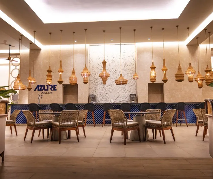 Sala con sillones y l&aacute;mparas colgantes; muro con barra &ldquo;Azure&rdquo;