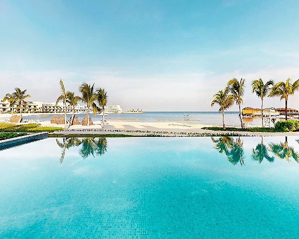 Piscina con palmeras y vista al mar en un hotel tropical