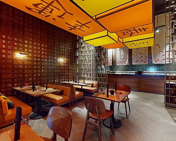 Interior con mesas, celdas doradas y murales, luces anaranjadas y letreros de caligraf&iacute;a