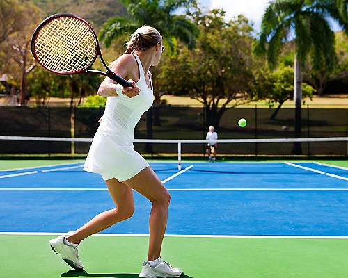 Mujer jugando tenis en una cancha azul al aire libre