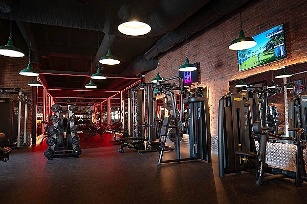 Gimnasio con m&aacute;quinas de pesas en un espacio de ladrillo y luces.
