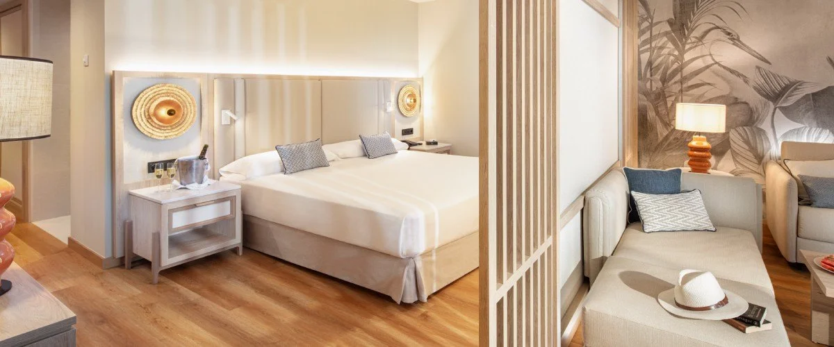 Dormitorio moderno con cama, sala de estar y decoraci&oacute;n tropical.