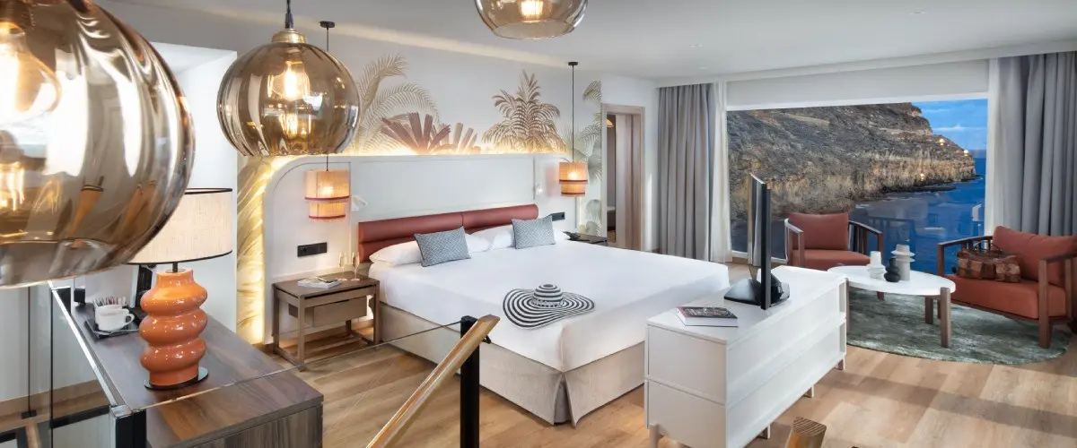 Dormitorio moderno con cama y balc&oacute;n con vista al mar y faros decorativos