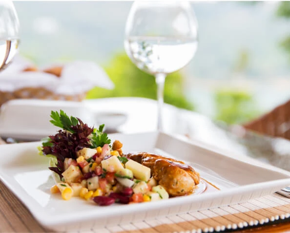 Plato de pollo con ensalada fresca y granos sobre mantel blanco.