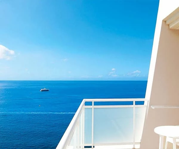 Balc&oacute;n con vista al mar azul y un barco en el horizonte