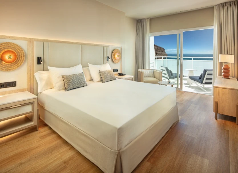 Dormitorio moderno con cama, ventanales y balc&oacute;n con vista al mar
