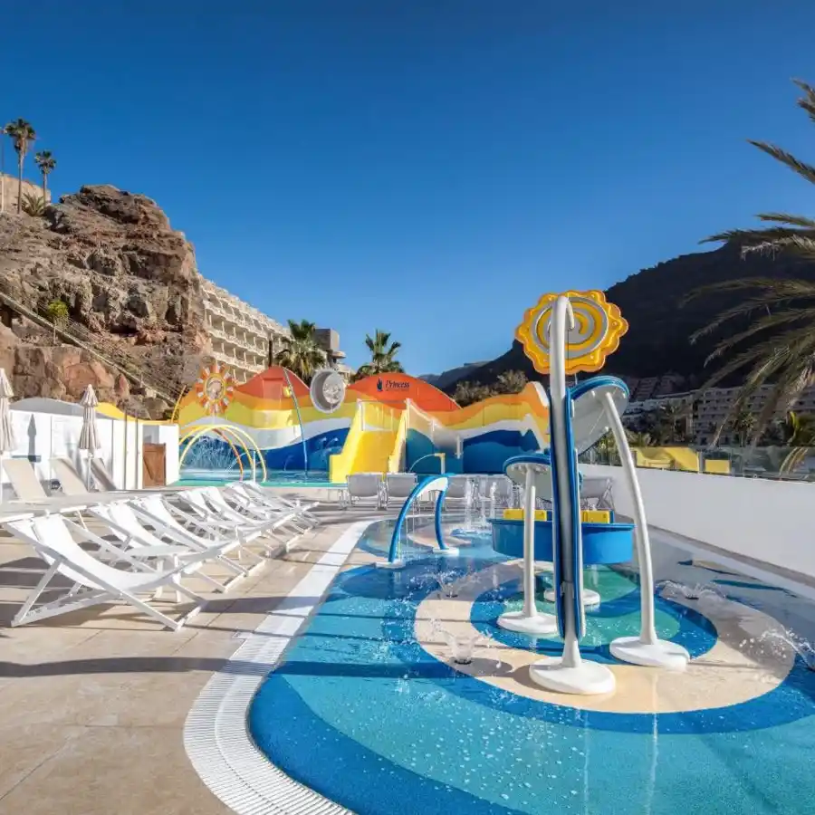 Piscina con tobog&aacute;n y juegos inflables frente a la monta&ntilde;a y palmeras.
