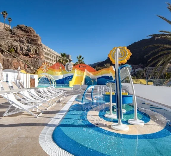 Piscina infantil con tobog&aacute;n y zona de juegos, junto al mar y monta&ntilde;as.