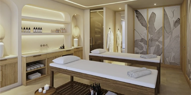 Sala de spa moderna con camillas, toallas y dispensador de aceite y vinos.