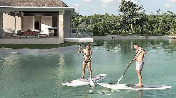 Dos mujeres hacen paddle surf frente a una casa junto al lago