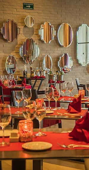 Mesa con copas y flores en comedor decorado con espejos dorados