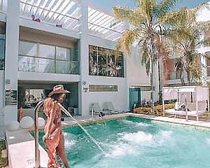 Mujer junto a una piscina en patio con palmeras y luz natural