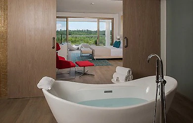 Ba&ntilde;o moderno con ba&ntilde;era blanca y vista al jard&iacute;n desde la ventana