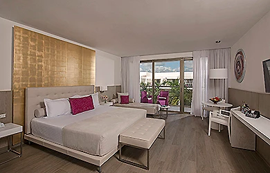 Dormitorio moderno con cama doble, sill&oacute;n y vista a un balc&oacute;n