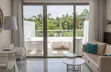 Sala luminosa con vista a una terraza y palmeras a trav&eacute;s de ventanales