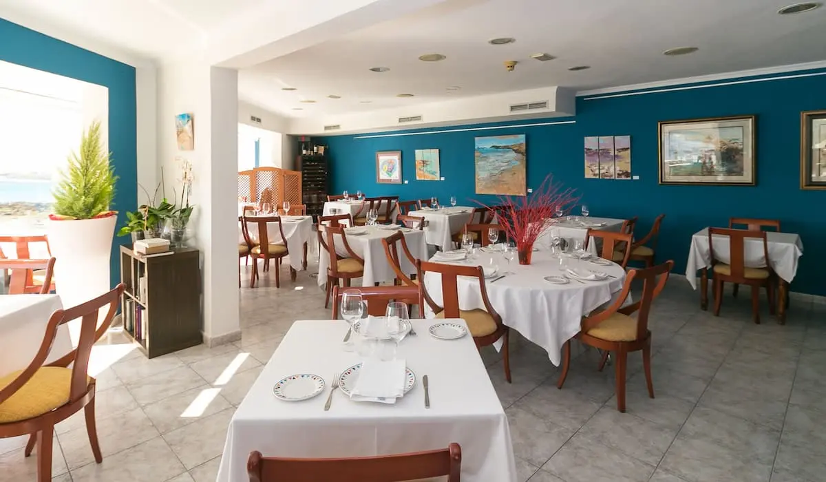 Comedor de restaurante con mesas cubiertas y paredes azules decoradas