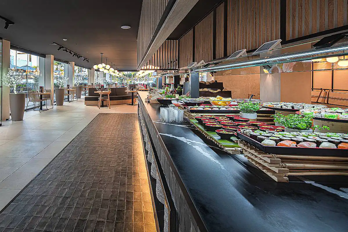 Buffet de ensaladas y verduras en un restaurante, con mesas y vitrina refrigerada