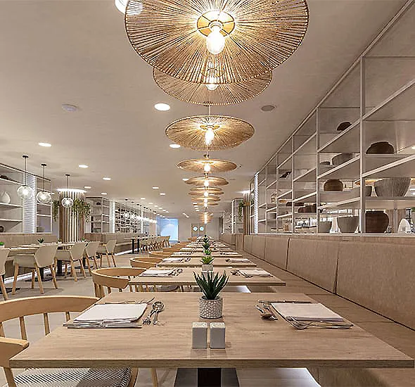 Comedor de estilo moderno con mesas largas y l&aacute;mparas de techo decorativas