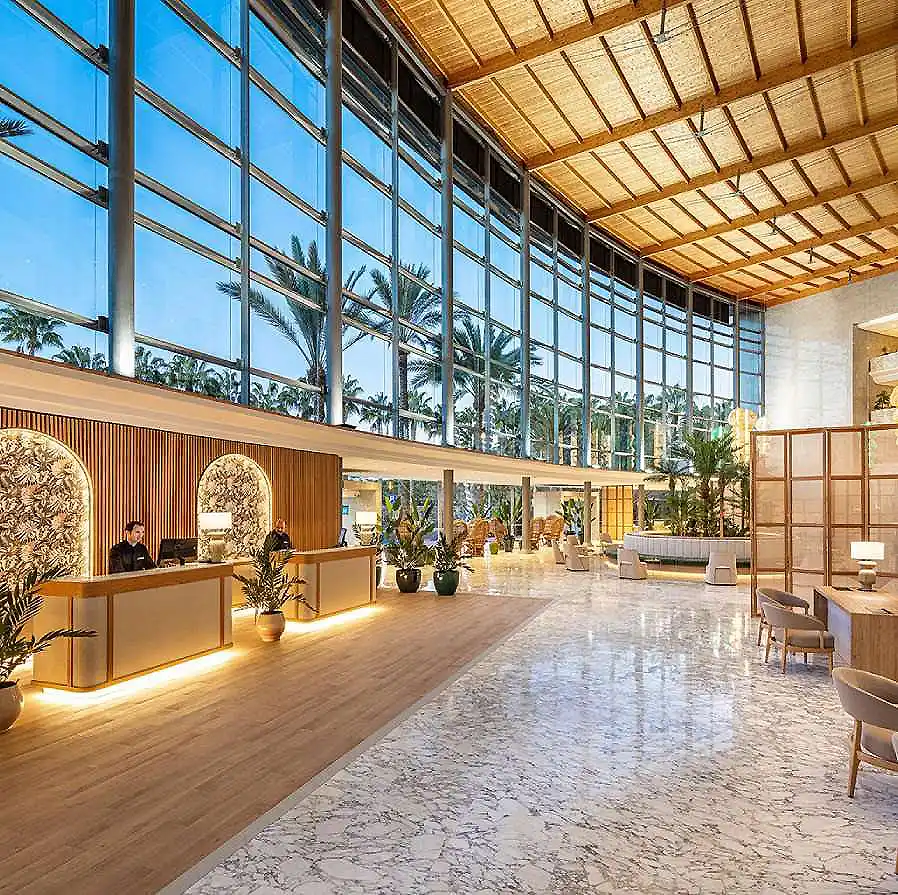 Lobby moderno con recepci&oacute;n, ventanales grandes y techo de madera.
