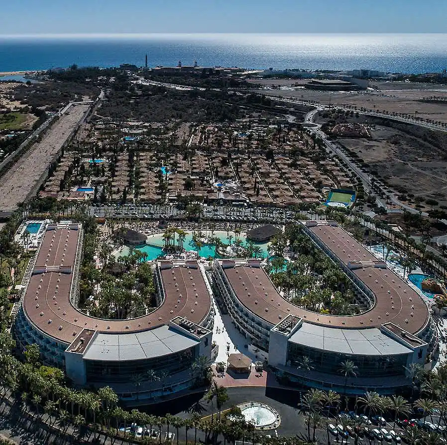 Vista a&eacute;rea de un hotel con piscinas y jardines junto al mar y la ciudad