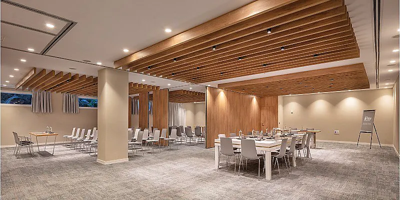 Sala de eventos con mesas, sillas y techo de madera abovedado.