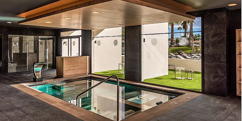 Piscina interior con sauna y &aacute;rea de descanso, luz natural y c&eacute;sped exterior