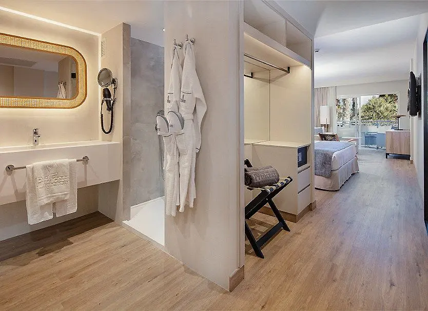 Ba&ntilde;o y vestidor con albornoz colgado y espejo; pasillo hacia la habitaci&oacute;n