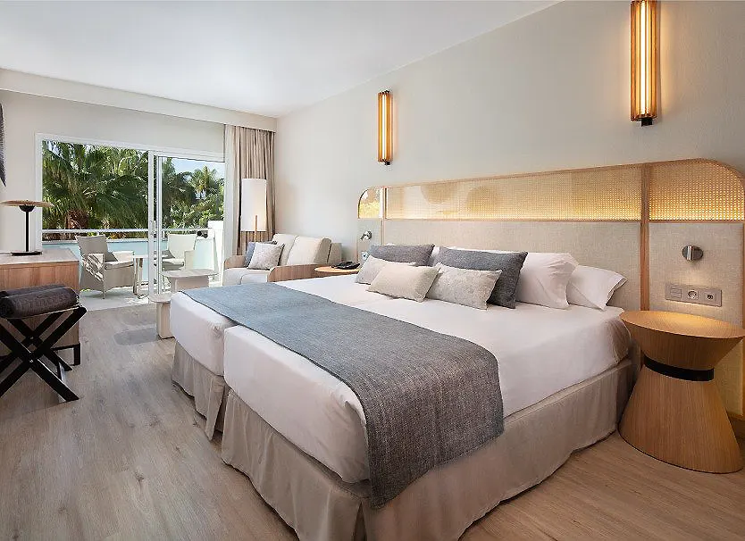 Habitaci&oacute;n de hotel moderna con cama doble, luces y terraza al fondo