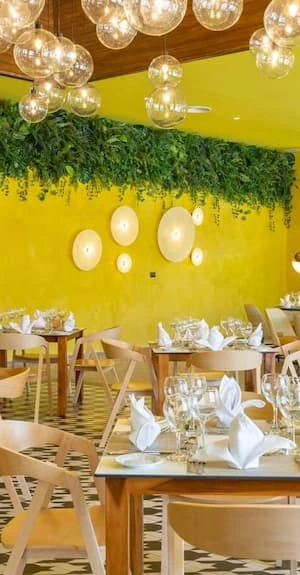 Comedor decorado con luces colgantes y mesa con copas, en sal&oacute;n amarillo