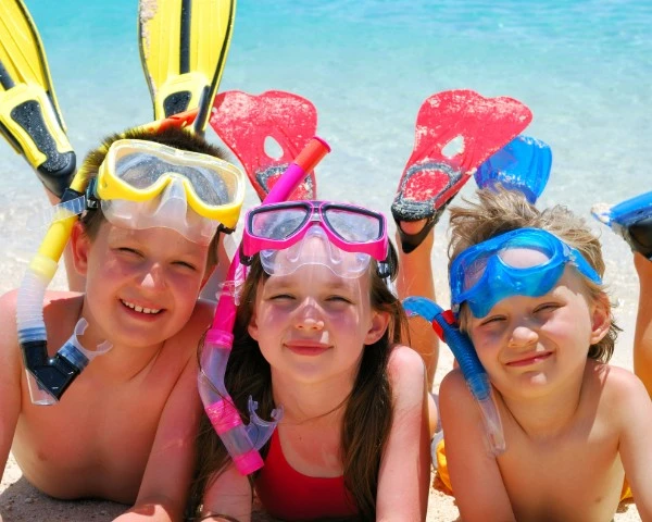 Cuatro ni&ntilde;os con m&aacute;scaras y aletas de buceo en el mar