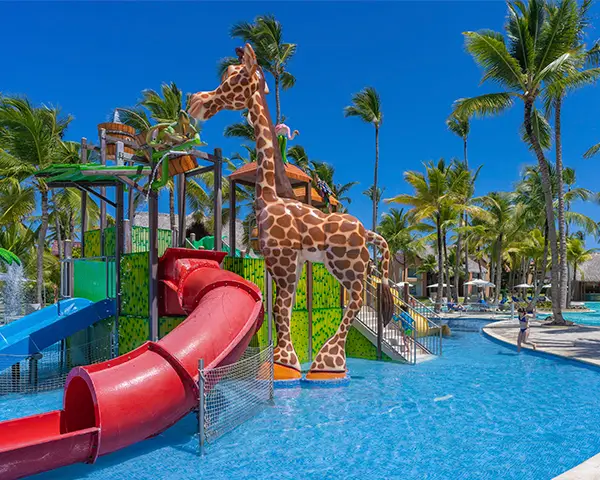 Jirafa decorativa junto a toboganes y piscina en parque acu&aacute;tico tropical