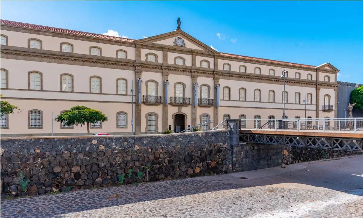 Fachada de edificio hist&oacute;rico con arcos, balcones y pared de piedra al frente