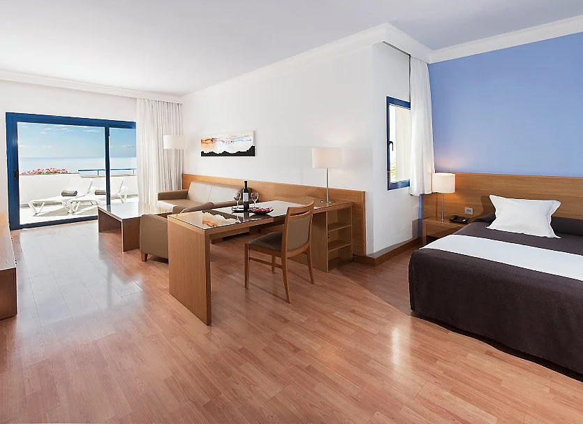 Habitaci&oacute;n moderna con cama, escritorio y gran ventana al mar