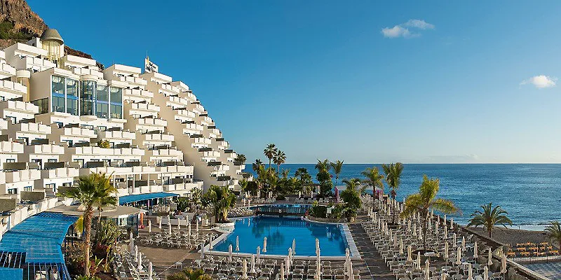 Hotel junto al mar con piscina y palmeras frente al oc&eacute;ano