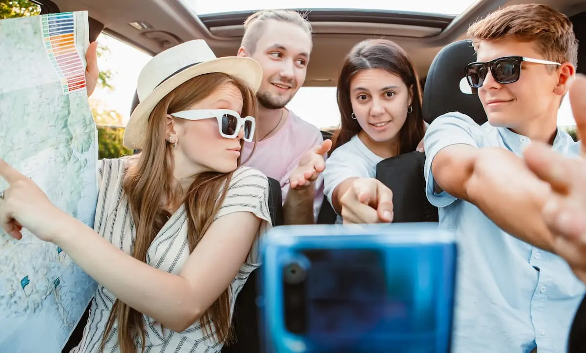 Grupo de j&oacute;venes en coche haciendo un selfie, con mapa y gafas de sol