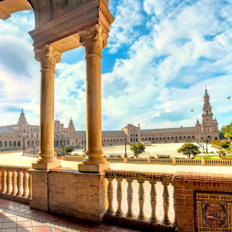 Plaza de Espa&ntilde;a en Sevilla vista desde un balc&oacute;n, con cielo azul y nubes.
