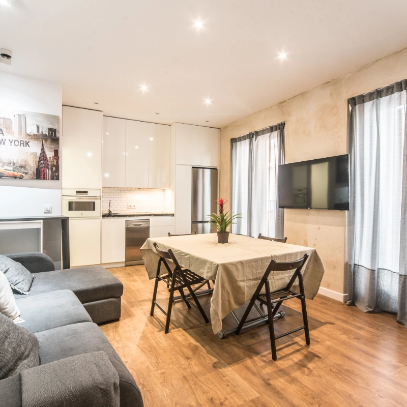 Sala moderna con cocina integrada, mesa, sof&aacute; y televisor.